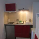 Petite cuisine avec plaques de cuisson, hotte, micro-ondes, évier et rangements