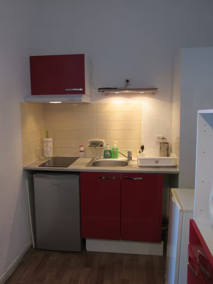 Petite cuisine avec plaques de cuisson, hotte, micro-ondes, évier et rangements